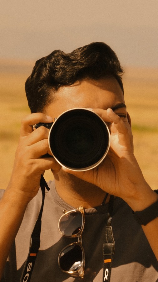 Krutik looking through a camera with a large lens